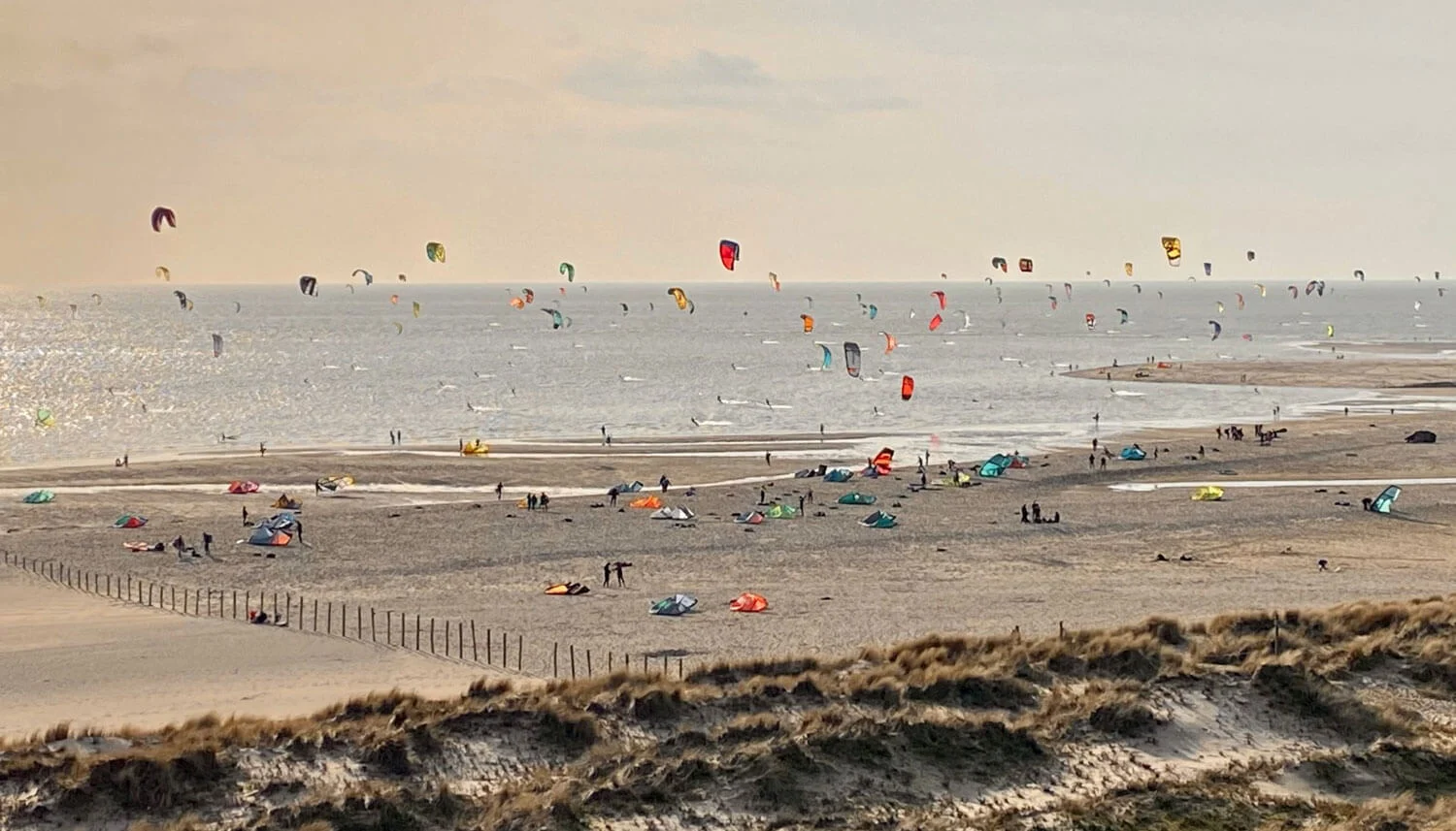 Het strand van De Slufter op de Maasvlakte 2: breed zandstrand, duinen en kitesurfers in de lucht